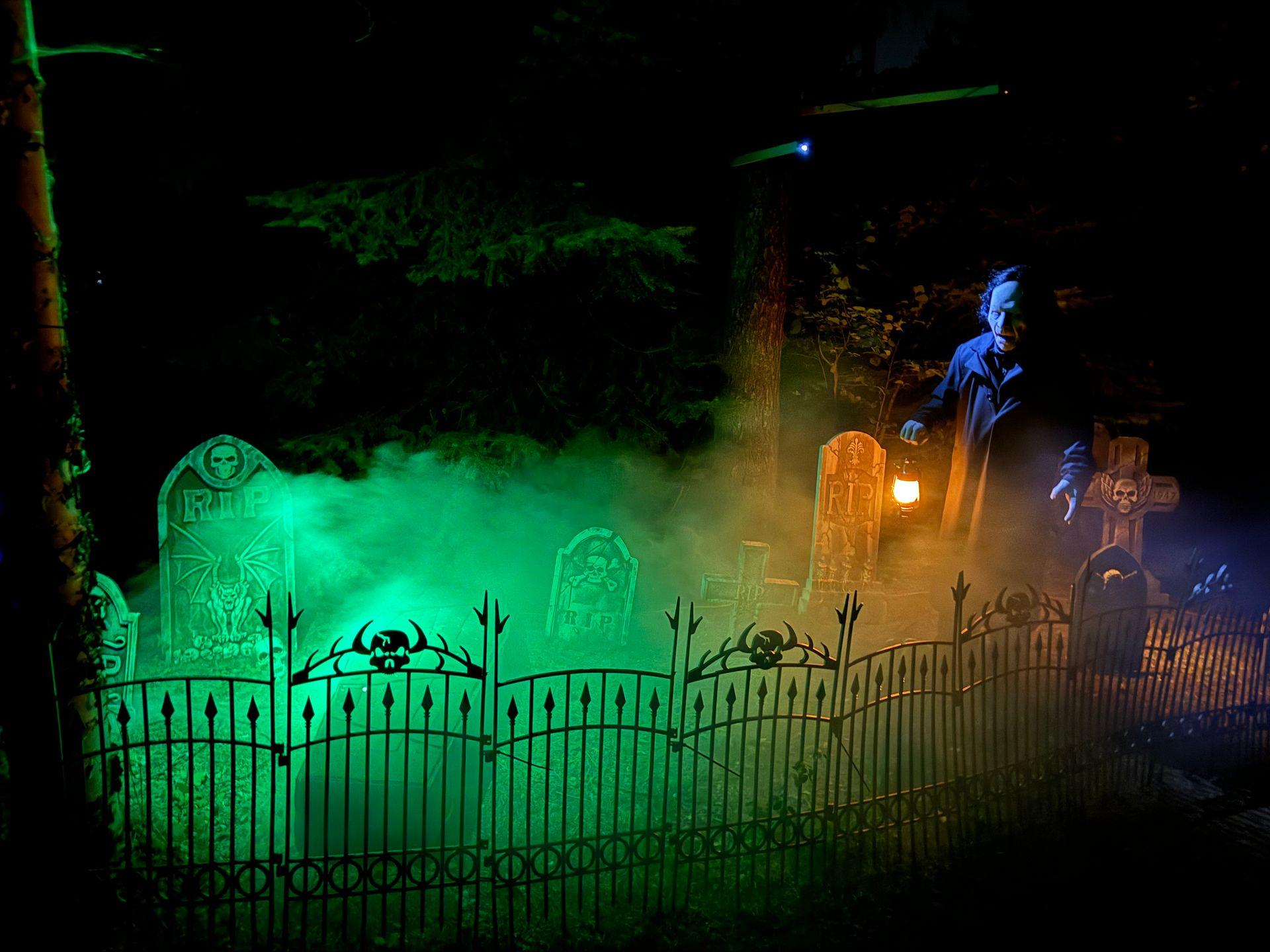 Spooky graveyard scene with tombstones, a gate, and green fog at night.